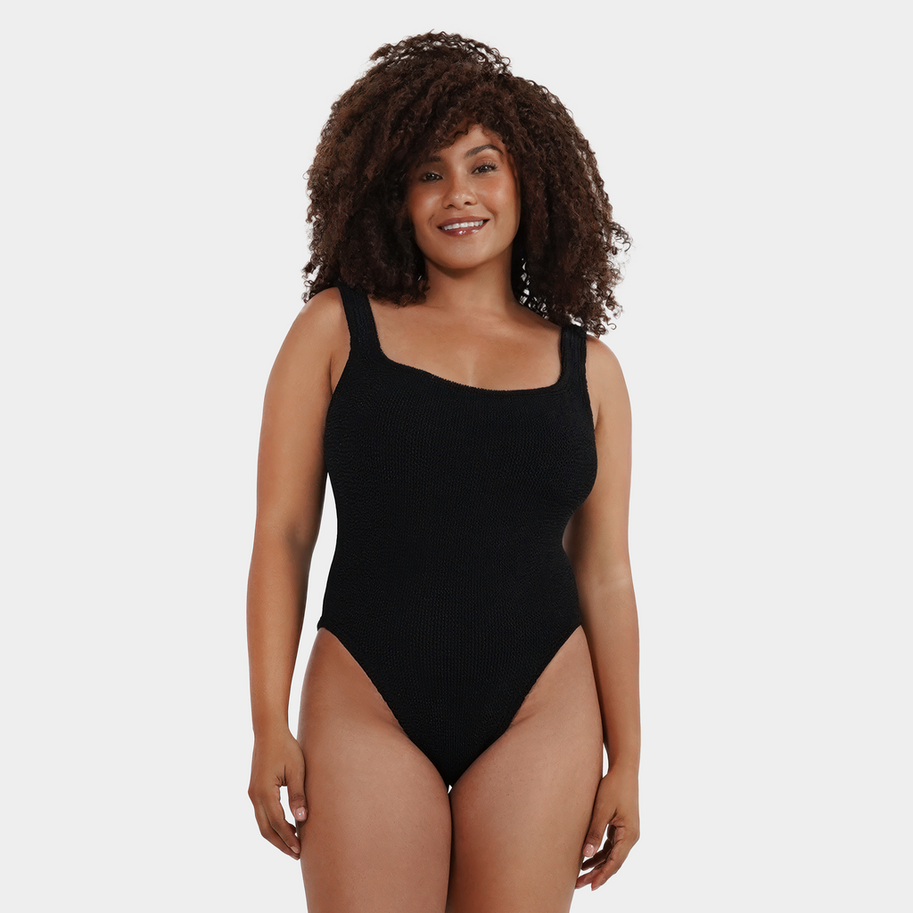 Model with curly black hair wearing the one size crinkle swimsuit in midnight black