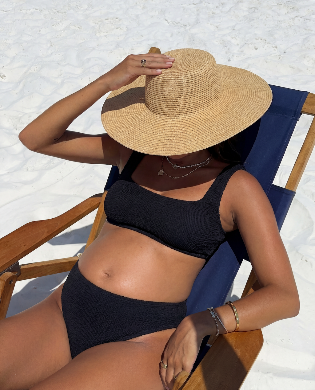 Model sitting in a deck chair wearing the high waisted crinkle bikini